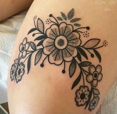 a woman's thigh with black and white flowers on the side, in front of her