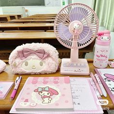 the desk has many items on it including a fan, notebooks and pen holder