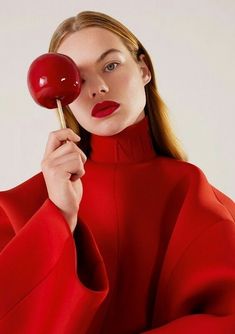 a woman in a red dress holding a lollipop