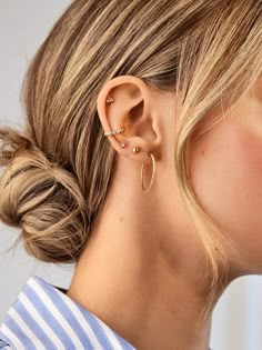 a woman wearing an ear cuff with two small gold hoops