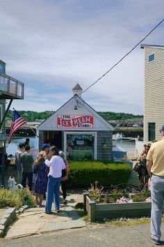 people are standing in front of the ice cream shop and looking at their surroundings outside