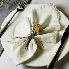 a white plate topped with a napkin covered in flowers next to two forks and knives