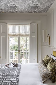 a bedroom with a bed, pillows and curtains