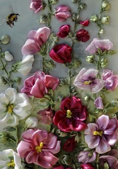 an arrangement of pink and white flowers with a bee on the wall in the background