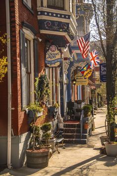 an american flag hanging from the side of a building on a city street with potted plants