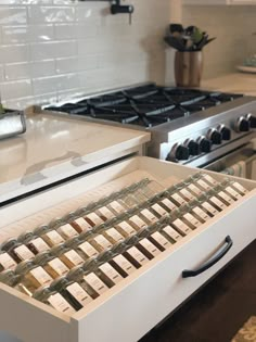 an open drawer in the middle of a kitchen counter with wine bottles on it and two stove top burners