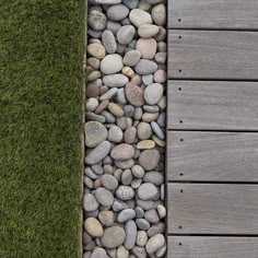 some rocks and grass next to a wooden walkway