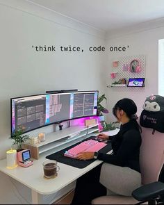 a woman sitting at a desk with two computer monitors and a keyboard in front of her