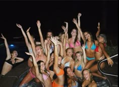 a group of women in bikinis are posing for a photo by the pool at night