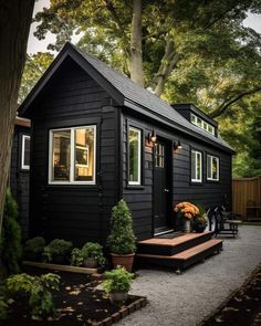 a small black house sitting next to a tree