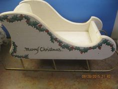 a wooden sleigh with holly and berries on the bottom is sitting in front of a blue wall