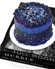 a blue cake with sprinkles on it sitting on top of a book