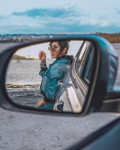 a woman taking a selfie in the side mirror of a car