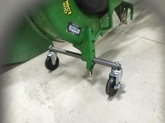 a green wheelbarrow sitting on top of a cement floor