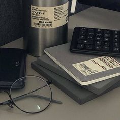 a stack of books next to a pair of glasses on top of a computer desk