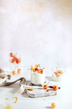 small desserts with cherries and whipped cream on a white tablecloth, ready to be eaten