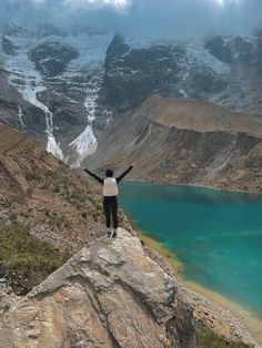 a person standing on top of a mountain with their arms in the air