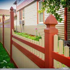 a red and white picket fence in front of a house with flowers growing on it