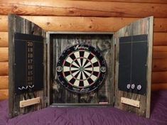 an open wooden box with darts in it on top of a purple bed sheet and wood walls