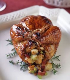 a white plate topped with meat covered in sauce and garnished with green herbs