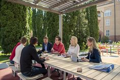 four people sitting at a picnic table talking to each other