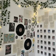 there are many records on the wall with vines growing over them and lights strung from above