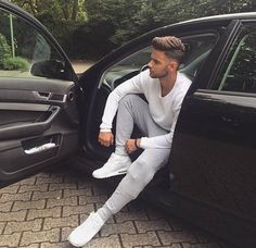 a man sitting in the open door of a car with his foot on the ground