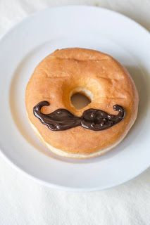 a donut with chocolate frosting and a mustache on the top is sitting on a white plate