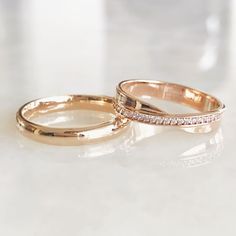 two gold wedding rings sitting on top of a white countertop next to each other