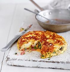 an omelet is cut in half on a cutting board next to a bowl