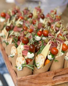 an assortment of appetizers in paper bags with tomatoes, olives and cheese