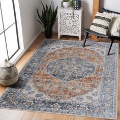 a living room area with a rug, chair and potted plant