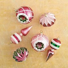 christmas ornaments are arranged on a wooden surface, including one pink ornament and the other red