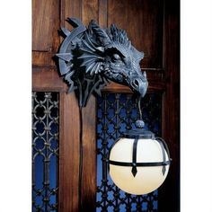 a dragon head mounted to the side of a wooden door next to a light fixture