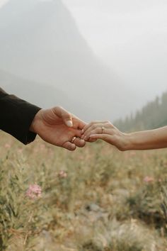 two people holding hands in the middle of a field