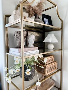 a shelf with flowers, books and pictures on it