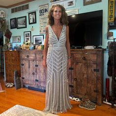 a woman is standing in front of a dresser and television set with pictures on the wall behind her