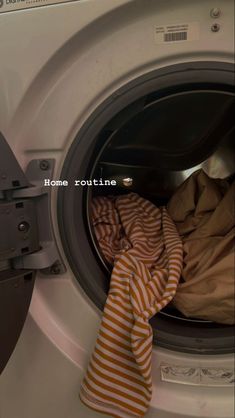 an orange and white striped towel sitting in front of a washing machine with the words home routine written on it