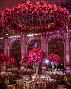 an elaborately decorated dining room with pink flowers and chandelier above the tables