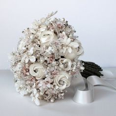 a bridal bouquet with white flowers and pearls on the bottom is sitting next to a pair of scissors