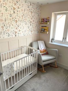 a baby's room with a rocking chair, crib and wallpaper on the walls