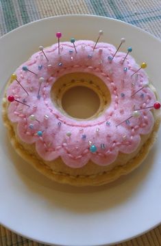 a donut with pink frosting and sprinkles sits on a plate