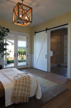 a bed sitting in a bedroom next to two doors and a light hanging from the ceiling