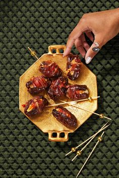 a person is picking up some food from a plate with skewers on it