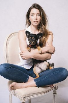 a woman sitting on a chair holding a small dog