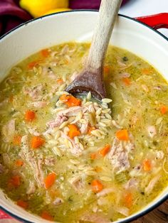 a wooden spoon in a bowl filled with chicken noodle soup on a red and white table cloth