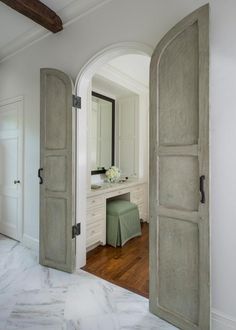 an open door leading to a bathroom with a vanity and dressing table in the background