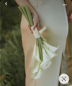 a person holding a bouquet of flowers in their hand and wearing a dress with an attached belt