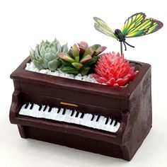 a planter with a butterfly sitting on top of it next to a piano keyboard