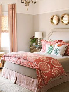 a bedroom with pink and white bedding, two round mirrors on the wall above it